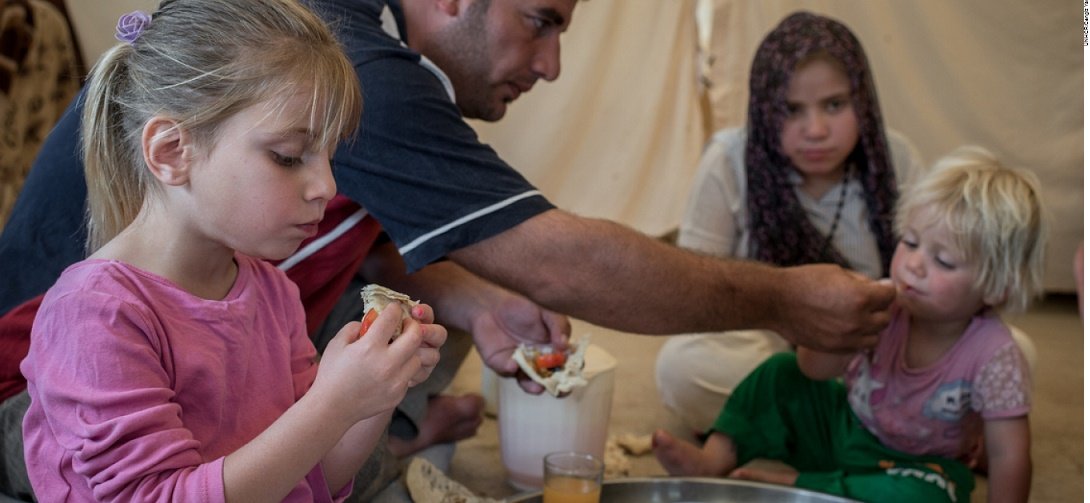 A displaced family from Mosul eat lunch at Baharka Camp on the outskirts of Erbil, Iraq. 